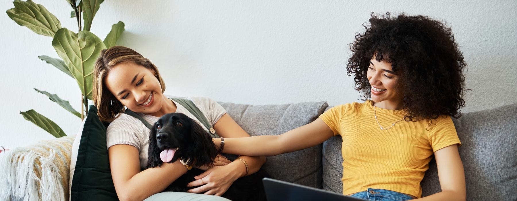 a couple of women sitting on a couch with a dog