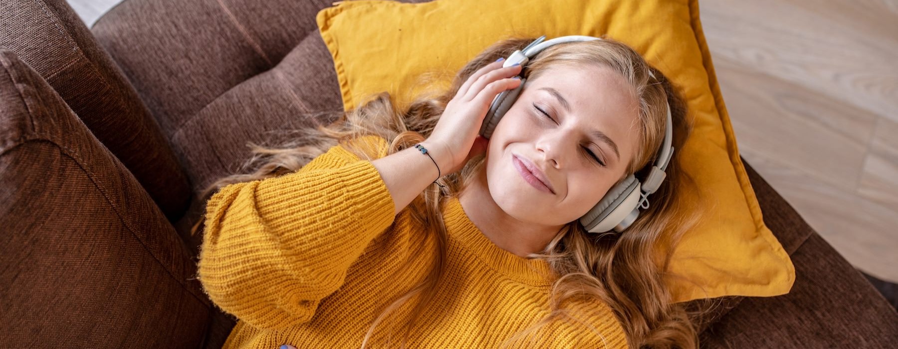 a woman on a sofa listening to headphones