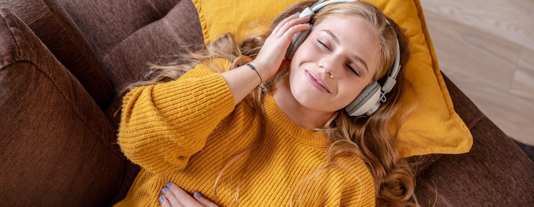 a woman on a sofa listening to headphones