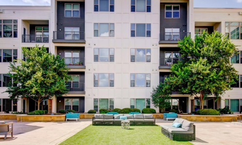 an apartment building with a lawn and trees